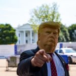 man wearing Donald Trump mask standing in front of White House